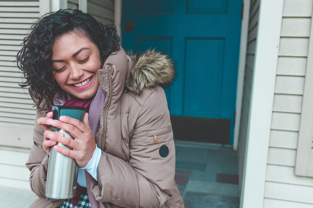 Femme souriante tenant sa tasse isotherme
